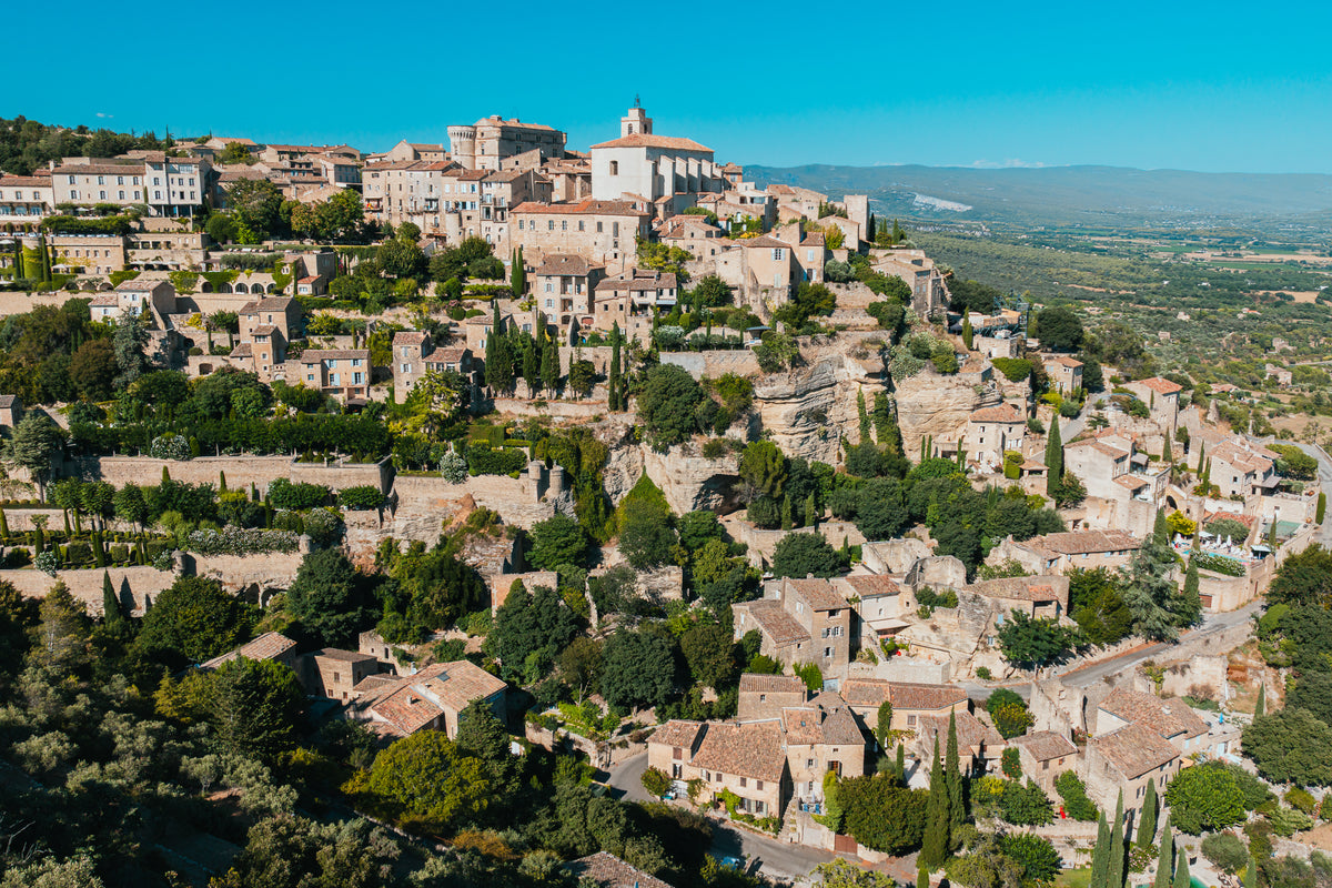 An aerial view of the historic stone buildings of Gordes village perched on a hill in Provence, France.