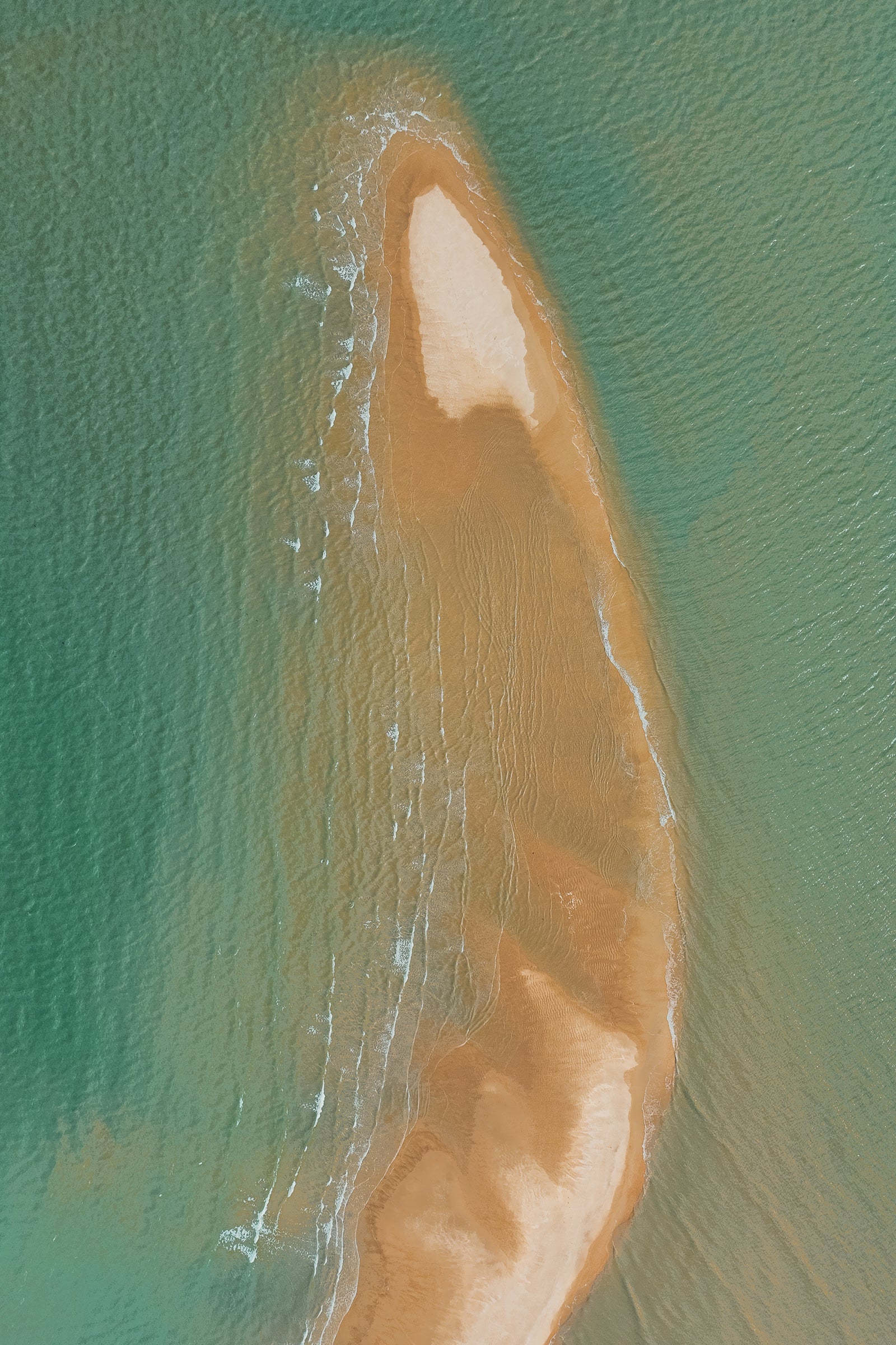 High-angle aerial view of a curved golden sandbar surrounded by clear turquoise ocean water.
