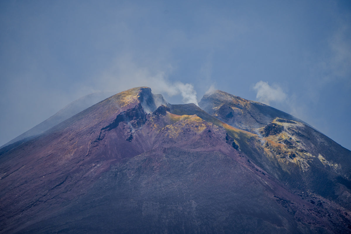 Close-up view of the smoking summit craters of Mount Etna in Sicily, showing yellow sulfur deposits and rocky terrain.