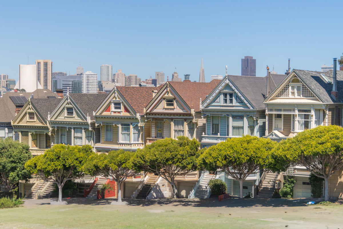 A row of colorful Victorian houses known as the Painted Ladies with the San Francisco city skyline in the background.