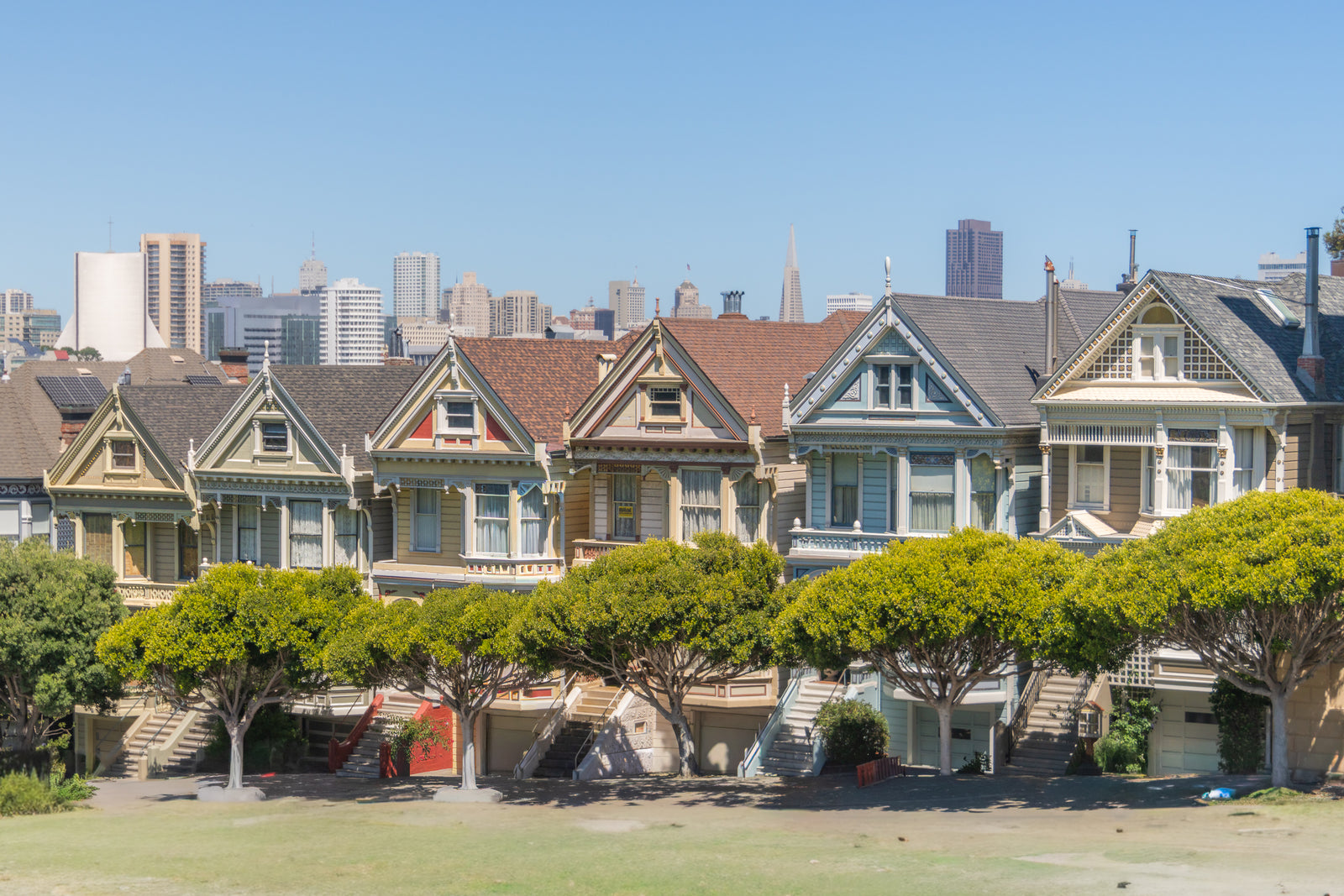 A row of colorful Victorian houses known as the Painted Ladies with the San Francisco city skyline in the background.