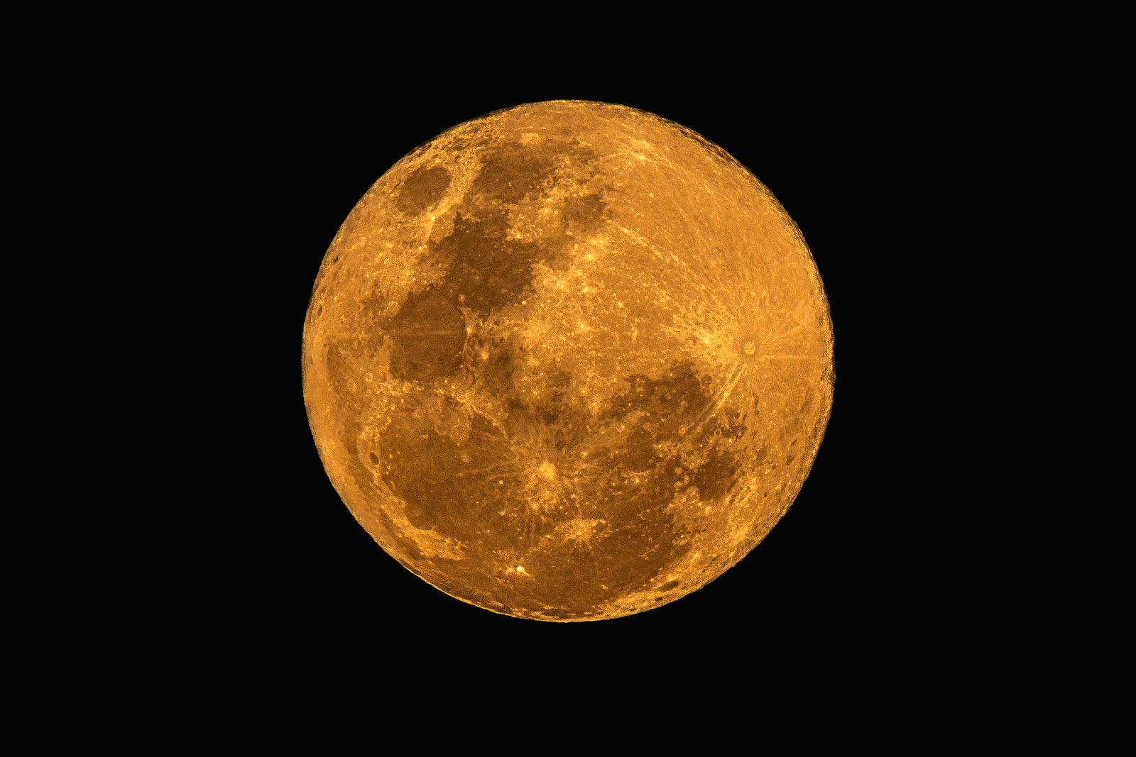 A detailed close-up photograph of a full moon glowing with golden and orange hues against a deep black sky.